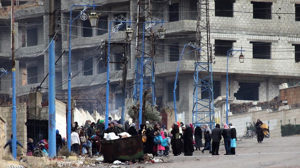 Syyrialaiset odottamassa humanitaarista apua miehitetyssä kaupungissa Damaskoksen ulkopuolella tammikuussa 2016.