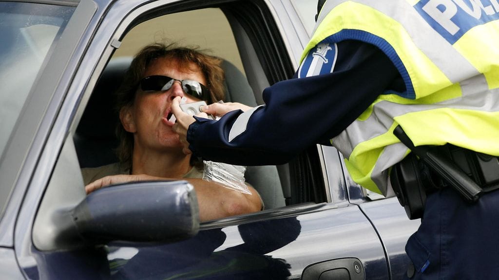 Poliisi puhalluttaa autoilijaa perinteistä pillialkometriä käyttäen.