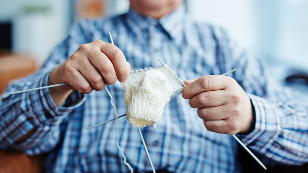 Neulomaan opetellut mies kertoo tekevänsä käsitöitä usein television katselun lomassa.
