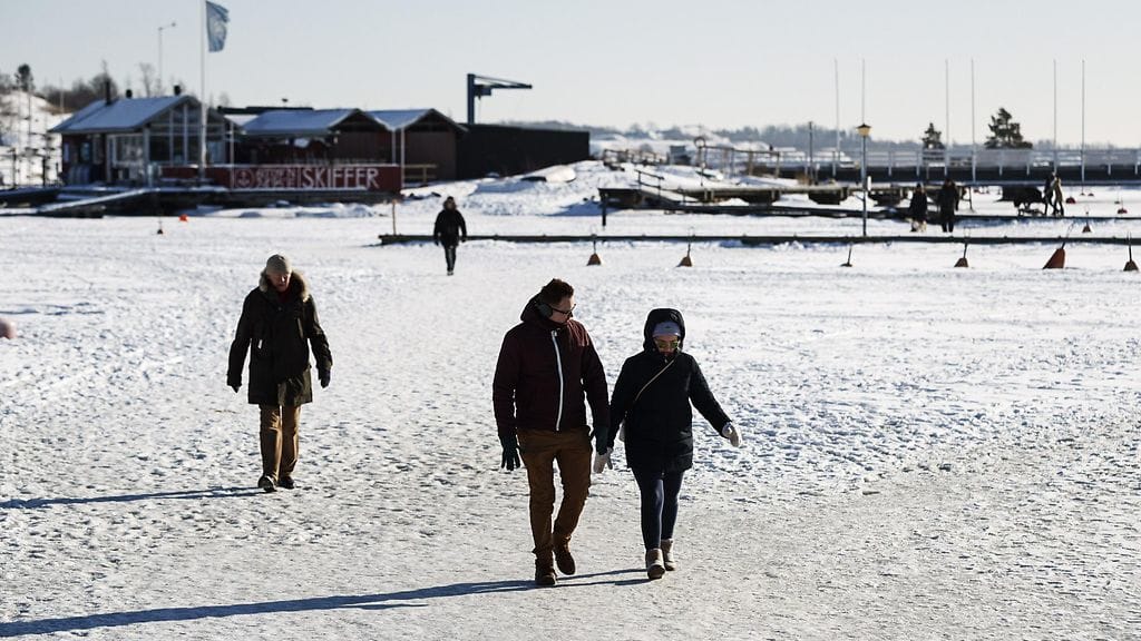 Ulkoilijoita kävelyllä jäällä kauniissa aurinkoisessa pakkassäässä Helsingin Merisataman edustalla Liuskasaaren vieressä tiistaina 20. helmikuuta.
