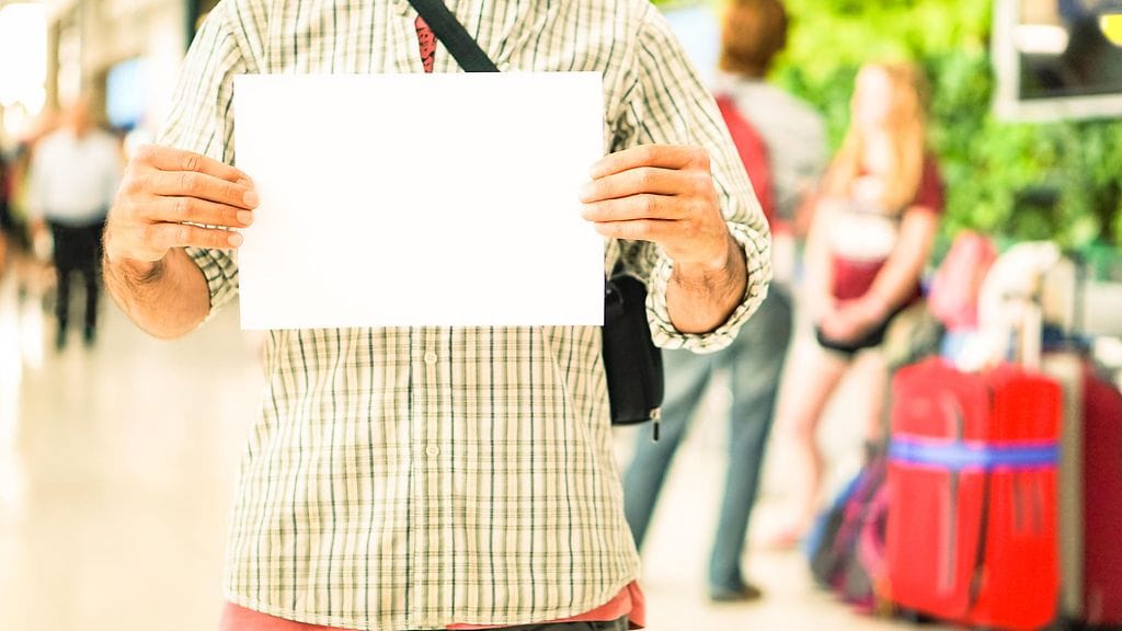 Petetty mies odotti kumppaniaan paljonpuhuvan kyltin kanssa. Kuvituskuva.